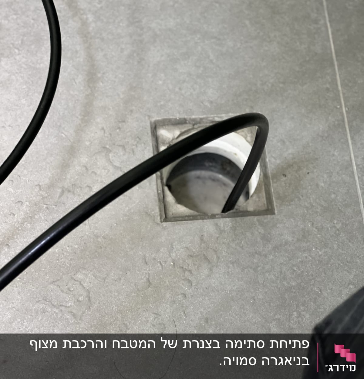 צינור שחור נכנס לניקוז ברצפה אפורה